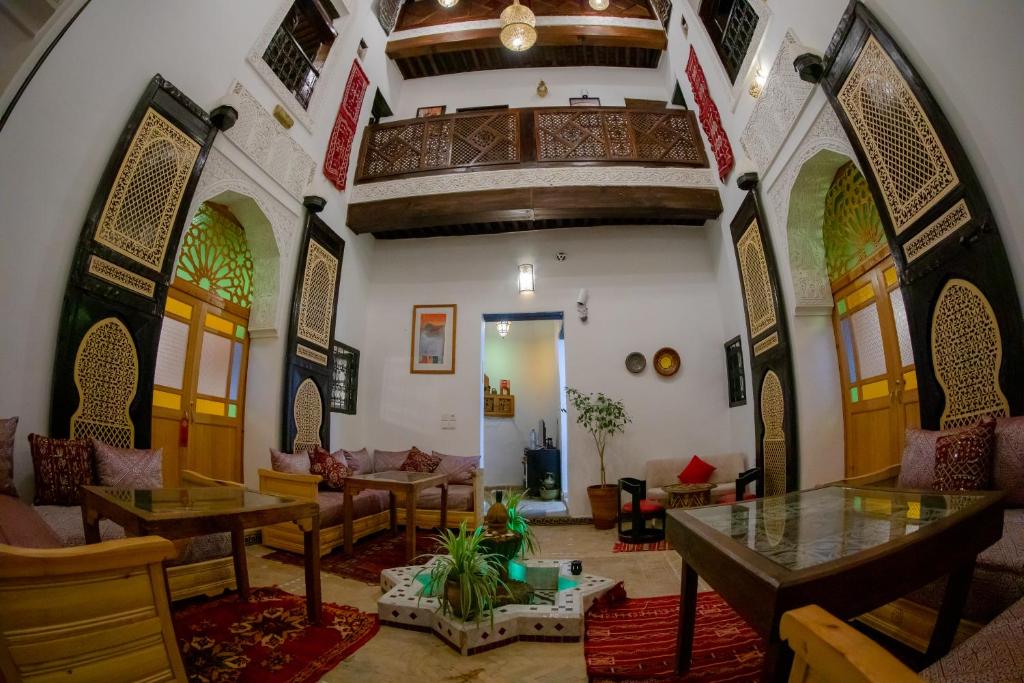 a living room with tables and chairs in a building at Shauala Riad - Where History Lives in Fès