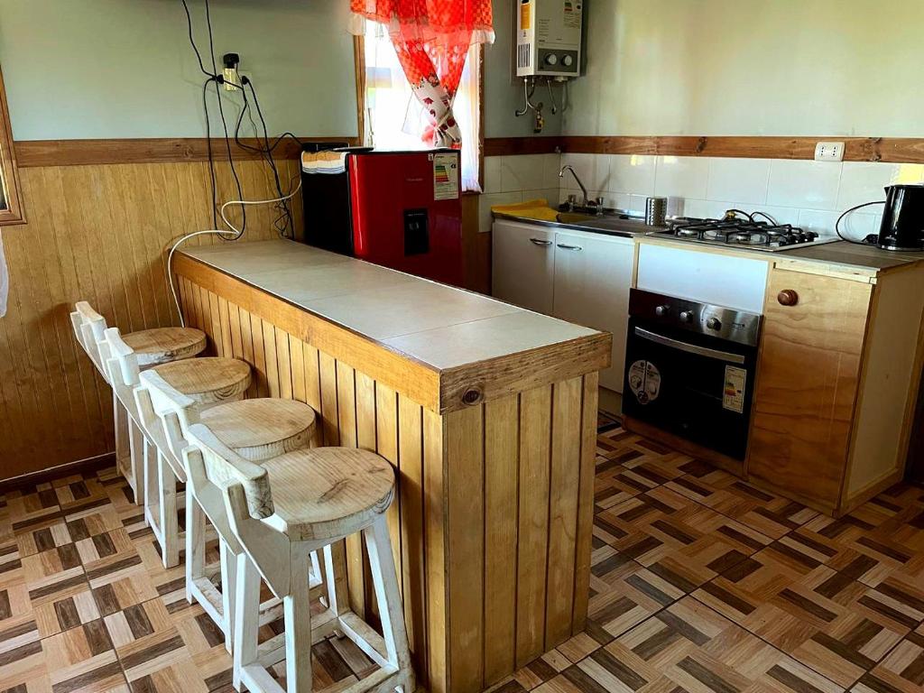 eine Küche mit einer Theke mit Hockern drum herum in der Unterkunft Cabaña equipada a 5 minutos de Panguipulli in Huellahue