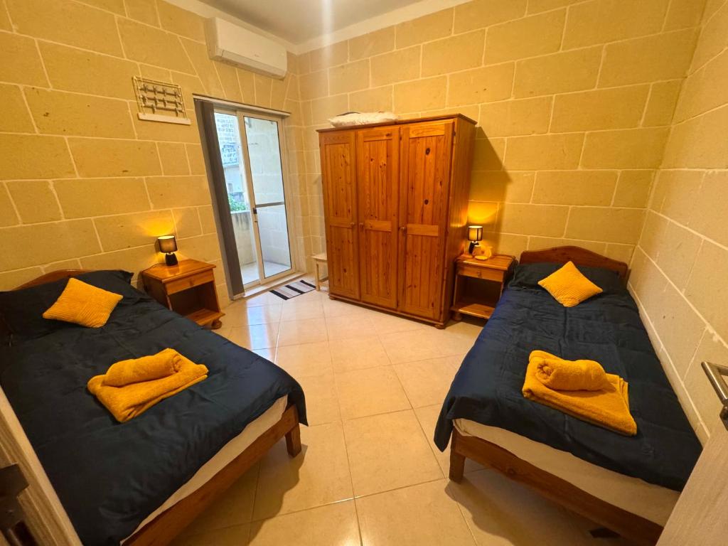 una camera con due letti con asciugamani gialli di St Anglu Xaghra - Quality Guest House a Xagħra