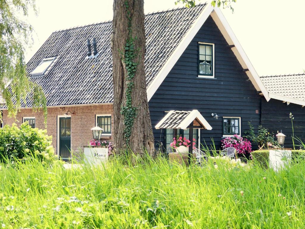 Una casa negra con un árbol delante. en Boerderij Honswijck en Weesp