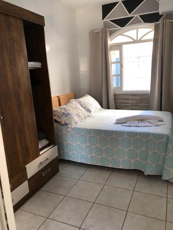 a bedroom with a bed and a dresser and a window at Kitnet centro de bombinhas in Bombinhas