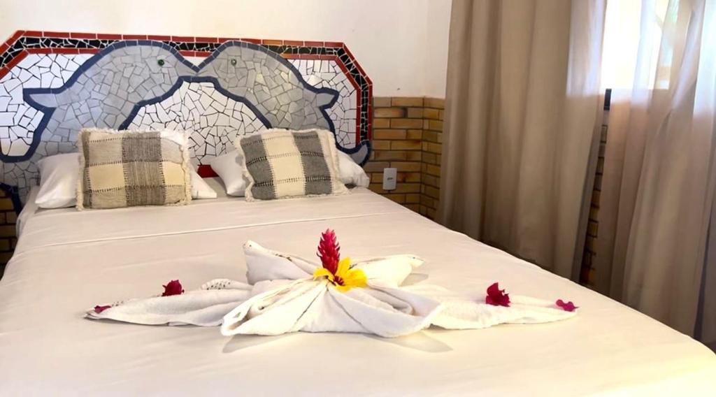 a bed with white towels and flowers on it at Pousada Praia do Amor Pipa in Pipa