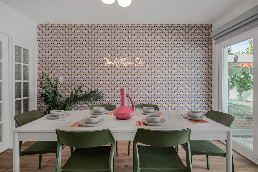 a dining room with a white table and green chairs at The Art Deco Den in Tampa