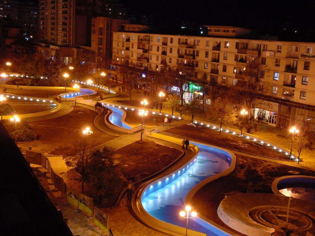 una strada di città di notte con luci ed edifici di Central suite a Piteşti