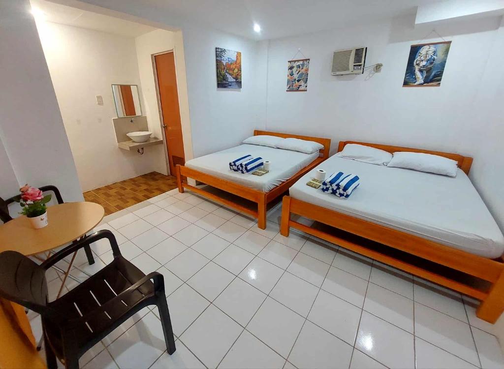 a bedroom with two beds and a table and a chair at RenSea Haven Boracay Rm10 in Boracay