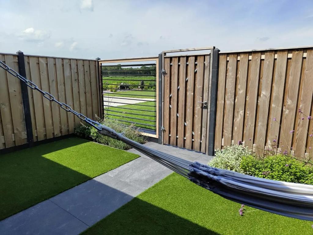a hammock in a garden with a fence at B&B de Gouden Ploeg met Jacuzzi in Bergentheim