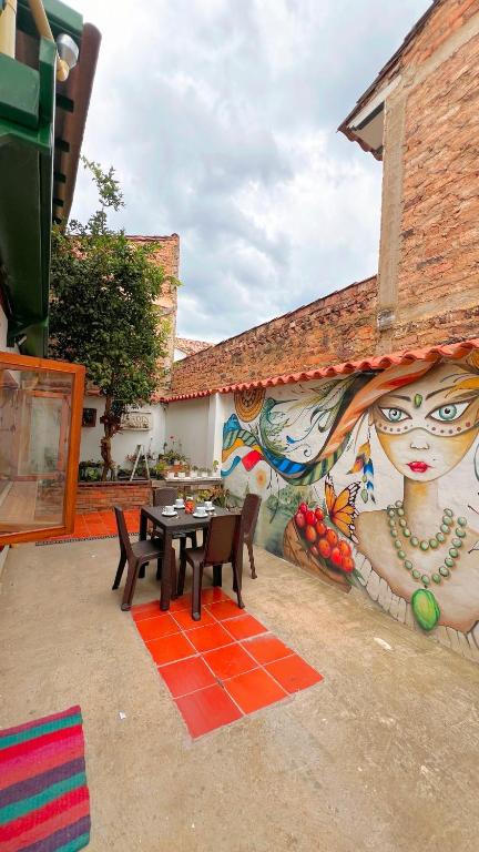 a patio with a table and a wall with a mural at Alta Vibracion Casa Boutique in Villa de Leyva