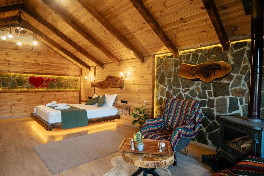 Cette cabane en rondins comprend un lit et une cheminée. dans l'établissement Mezrasuit Bungalov, à Çamlıhemşin