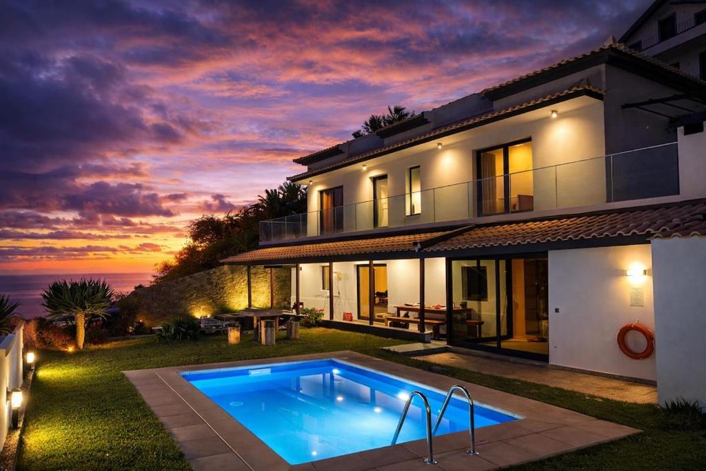 a house with a swimming pool in front of it at Villa Barros in Câmara de Lobos