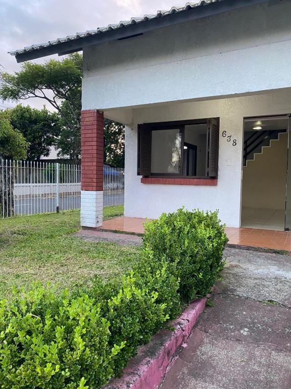 a white house with a window and some bushes at Casa para Pernoite no Centro de Osório in Osório