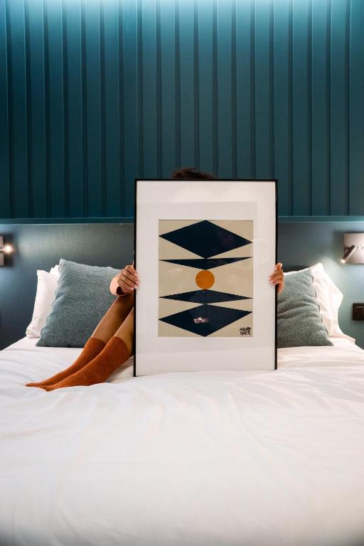 a person holding up a picture on a bed at BYPILLOW Bilbo in Bilbao