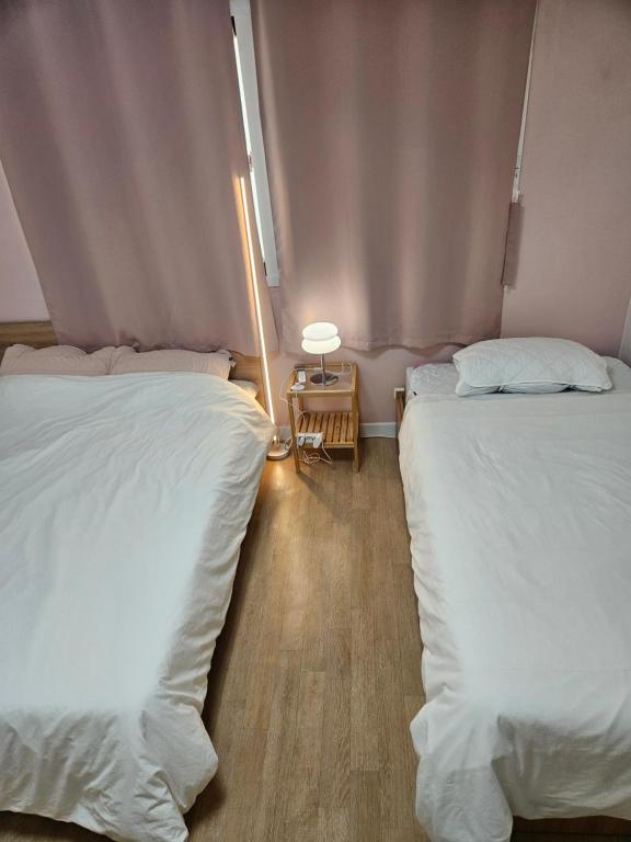 una camera da letto con due letti e un tavolo con una lampada di Hongdae ssuny house a Seul