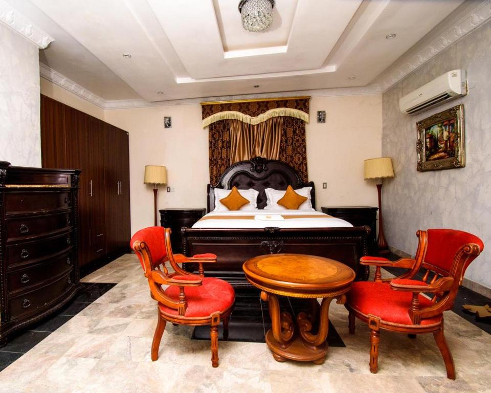 a bedroom with a bed and a table and chairs at GALLANISUITES hotels in Ibadan