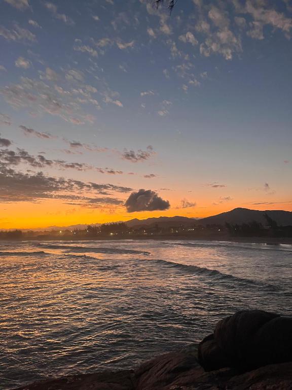 a sunset on the beach with the ocean at Residencial Bambu in Garopaba