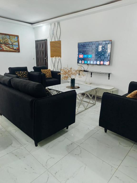 a living room with couches and a tv on a wall at Résidence meuble in Abidjan