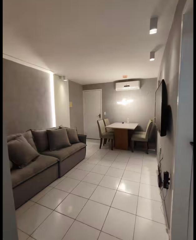 un soggiorno con un divano e un tavolo di Ótima localização 20 min Pajucara a Maceió