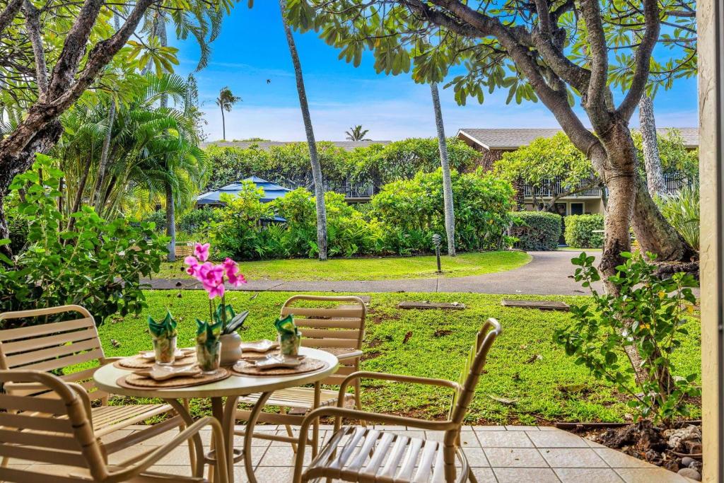 een patio met een tafel met stoelen en bloemen erop bij Napili Shores D125 in Honokowai