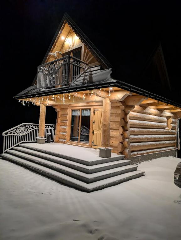 a log cabin with a balcony and stairs at Drewniane Zacisze in Biały Dunajec