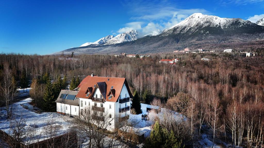 een oud gebouw met een met sneeuw bedekte berg op de achtergrond bij Penzión Chata Valaška in Stary Smokovec