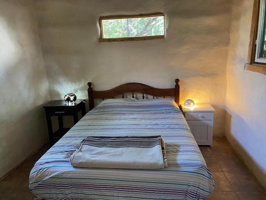 een bed in een kleine kamer met een raam bij Icho's mud house in Villa Icho Cruz