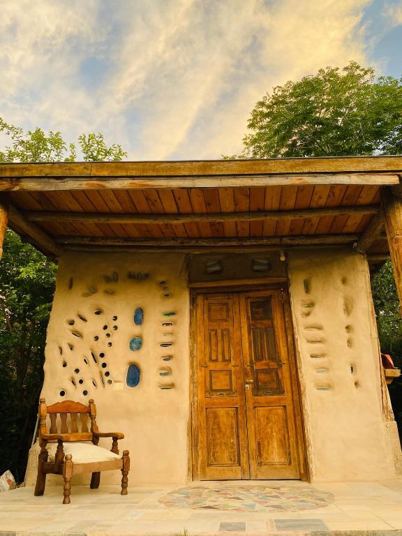a house with a wooden door and a bench in front at Icho's mud house in Villa Icho Cruz