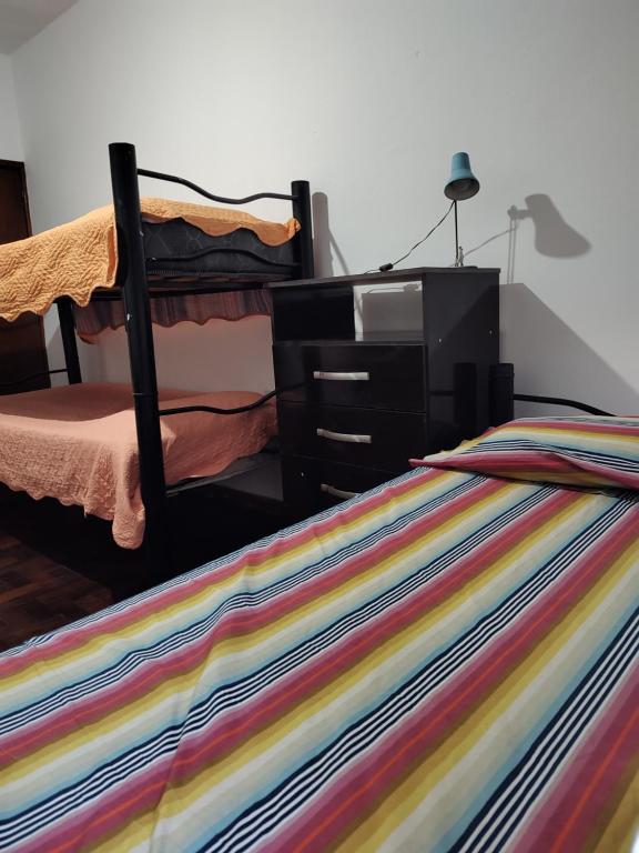 een bed met een commode en een kleurrijke gestreepte deken bij HA! 2 Resi para estudiantes in Cordoba