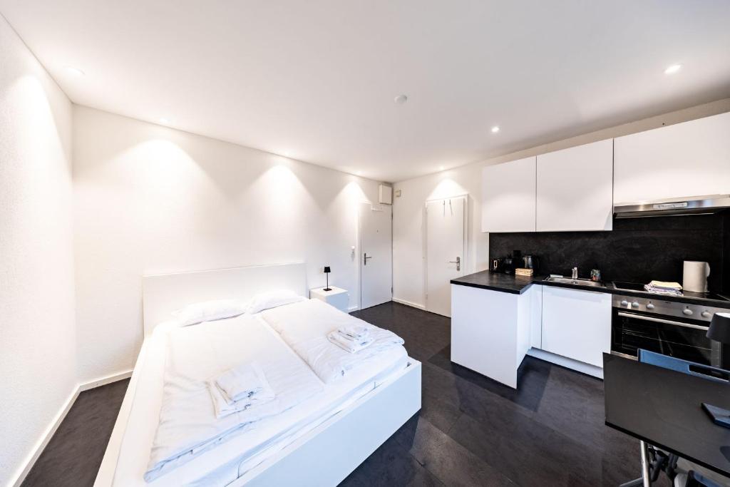 a white room with a bed and a kitchen at Lea Apartement - Ruhiges Studio in Schaffhausen