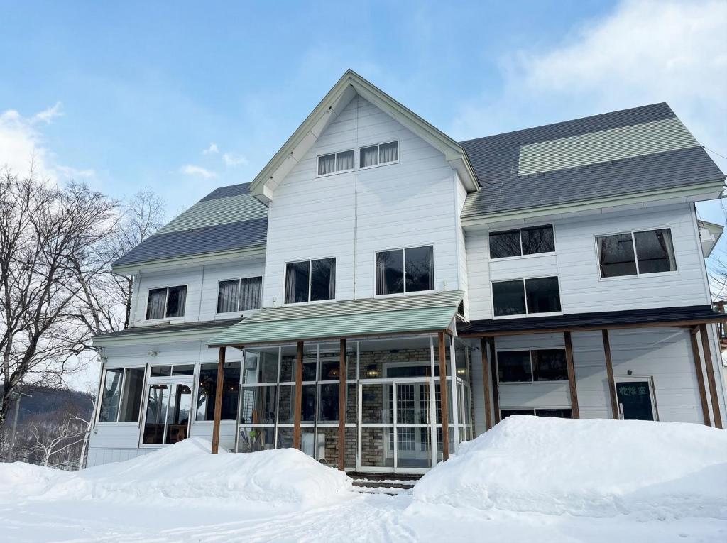 a white house with snow in front of it at Kamoshika Lodge Hakuba in Minami Otari