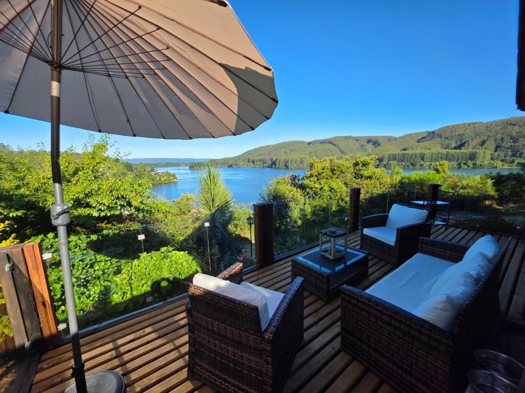 een terras met stoelen en een parasol en uitzicht op een meer bij Casa Rio Valdivia in Valdivia