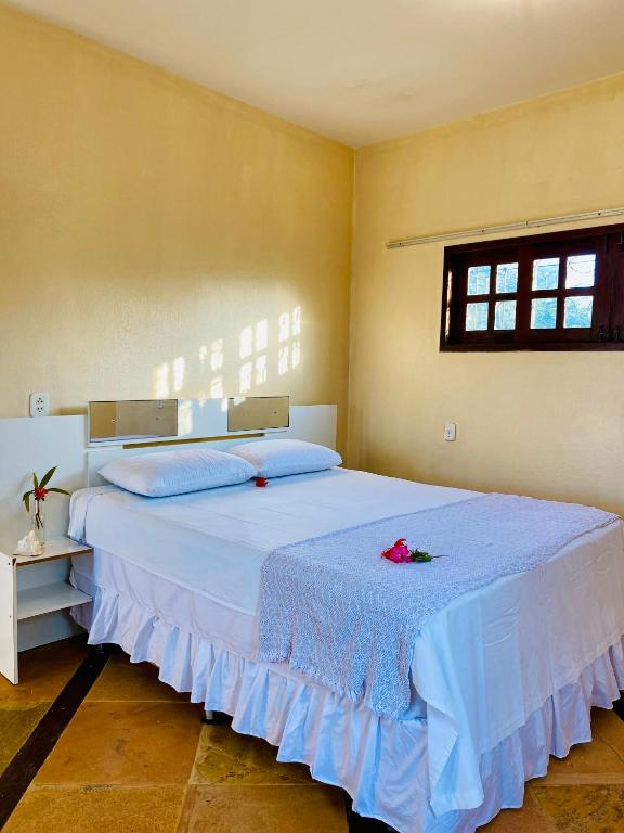 una camera da letto con un grande letto bianco con un fiore sopra di Casa Caju a Aracati