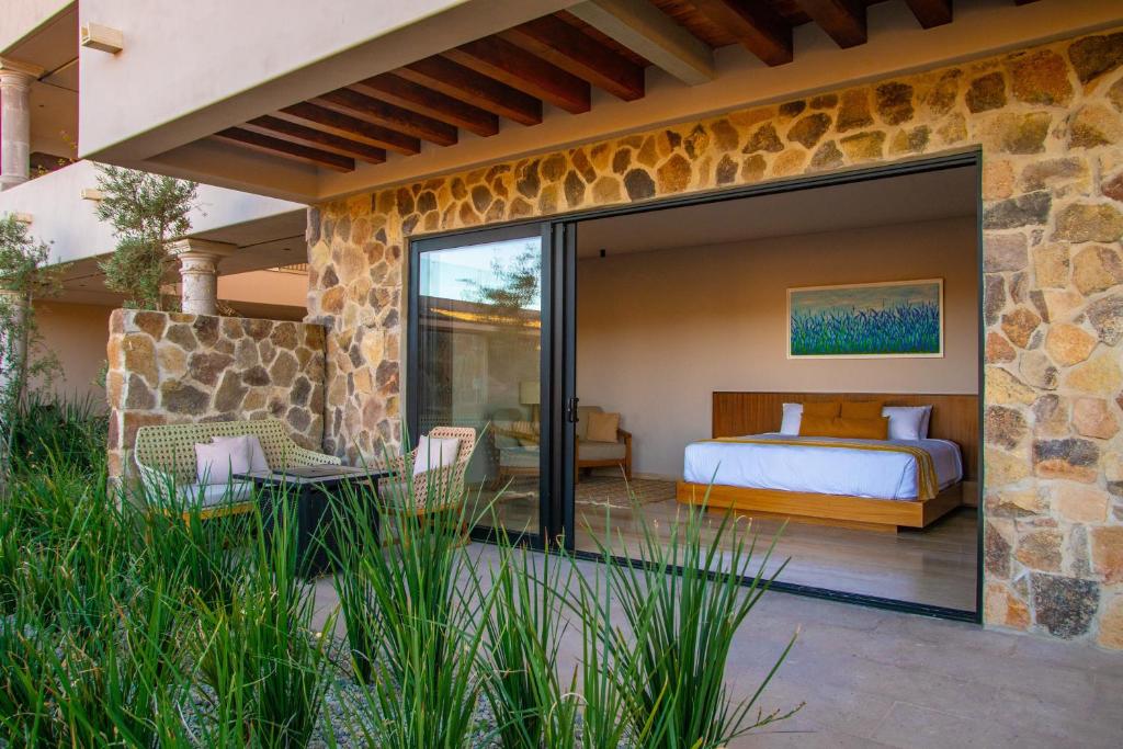 una camera da letto con un letto in un muro di pietra di Hotel Flores de Sal-Valle de Guadalupe a Valle de Guadalupe