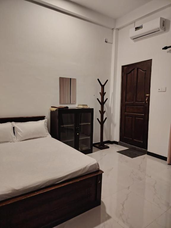 a bedroom with a bed and a wooden door at Cinnamon Shade by Achievers in Negombo