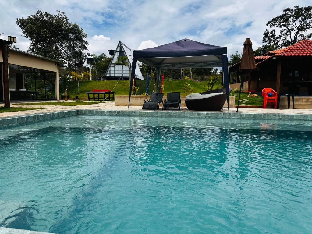 a swimming pool with chairs and a gazebo at Chácara mana in Anápolis