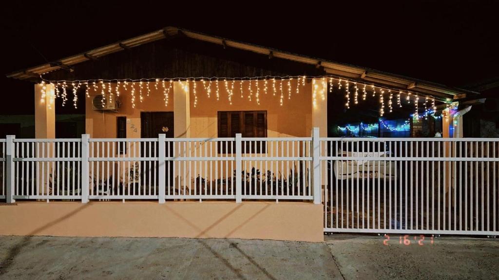 a house with a white fence and christmas lights at Habitación Familiar in Pântano Grande