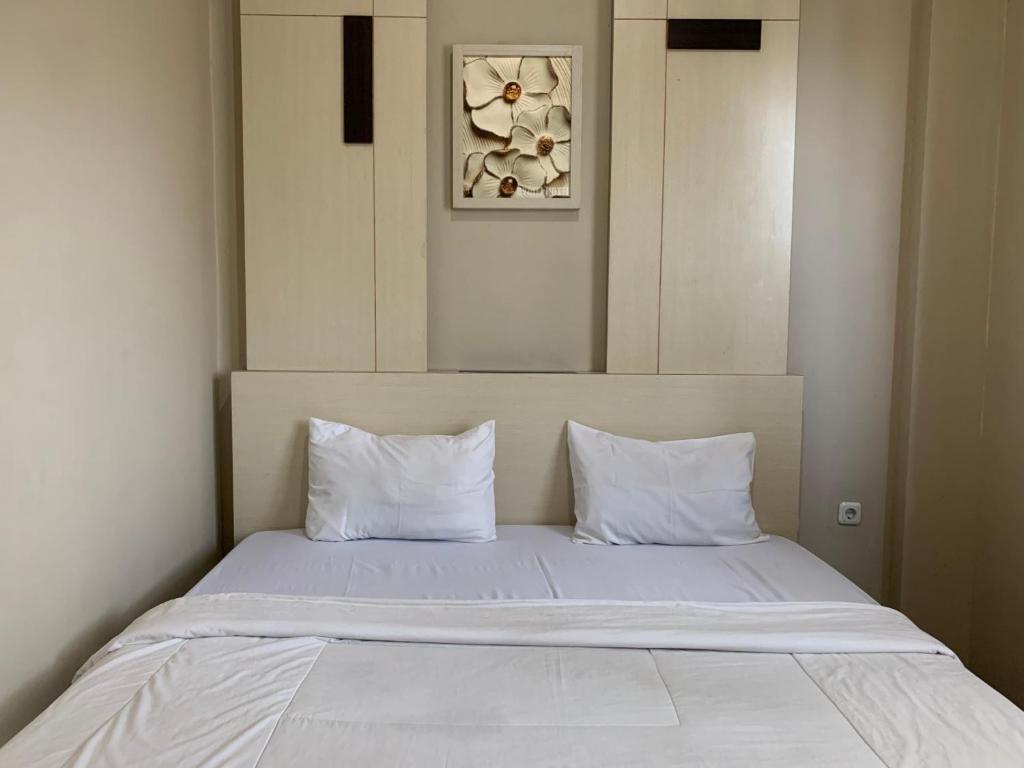 een bed met witte lakens en kussens in een kamer bij Grand Bydiel in Lanjang