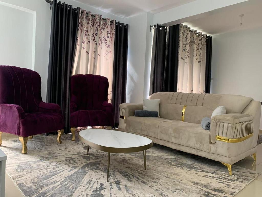 een woonkamer met een bank en twee stoelen bij Grey Nest Grey point 303 in Kericho