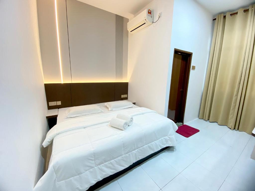 a bedroom with a large white bed with towels on it at Samudera Hotel in Kampung Kuala Besut