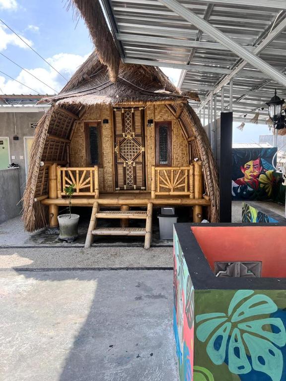 een kleine hut met een rieten dak bij The Twins Sunset Bungalow in Palebah