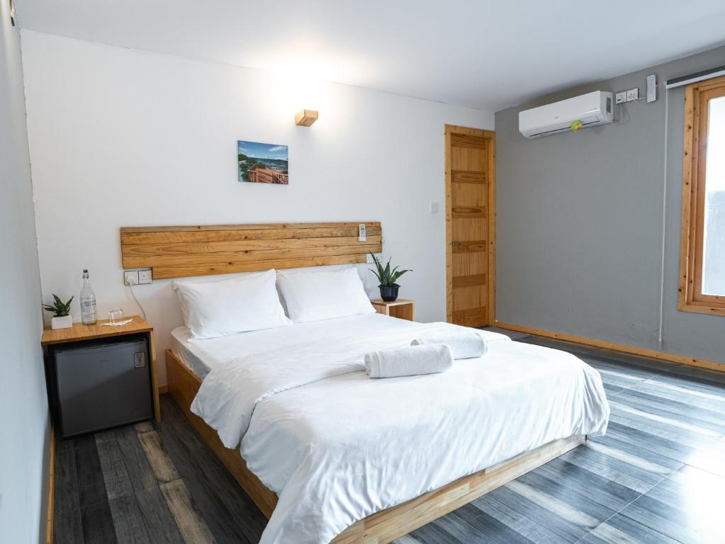une chambre avec un grand lit blanc avec une tête de lit en bois dans l'établissement Kanditheemu Inn, à Kanditheemu