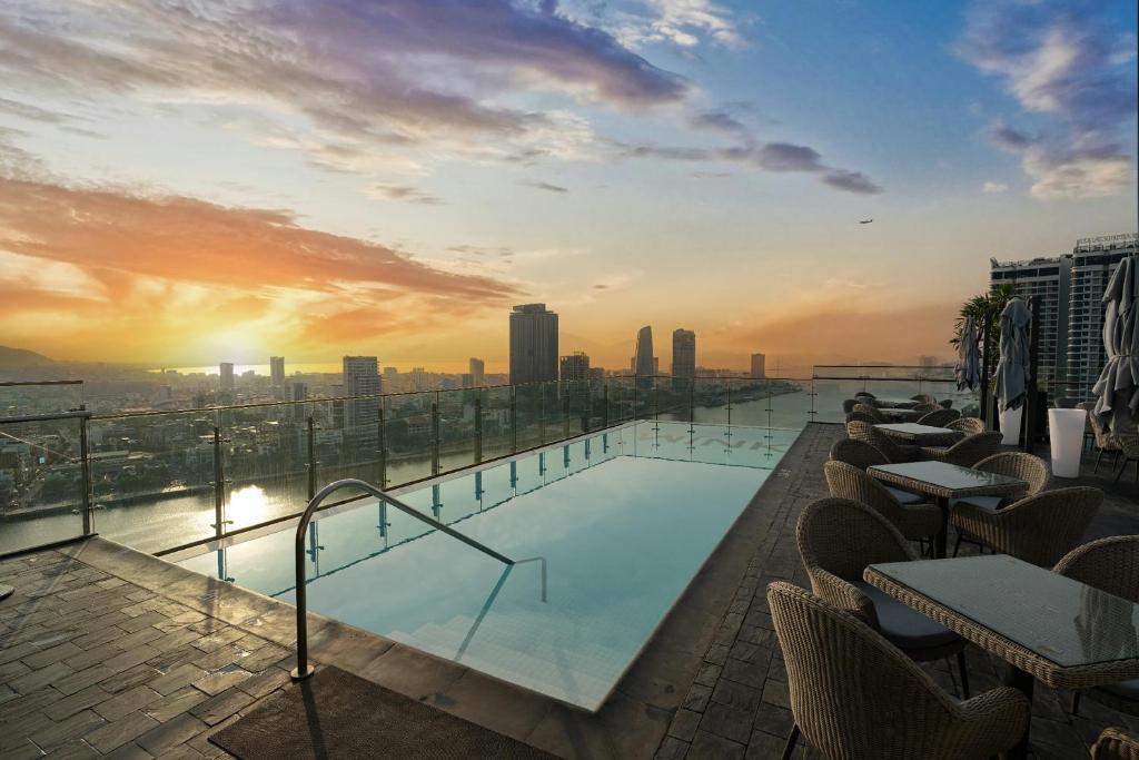 een zwembad op het dak van een gebouw met een zonsondergang bij Wink Danang Riverside, Unscripted by Hyatt in Da Nang