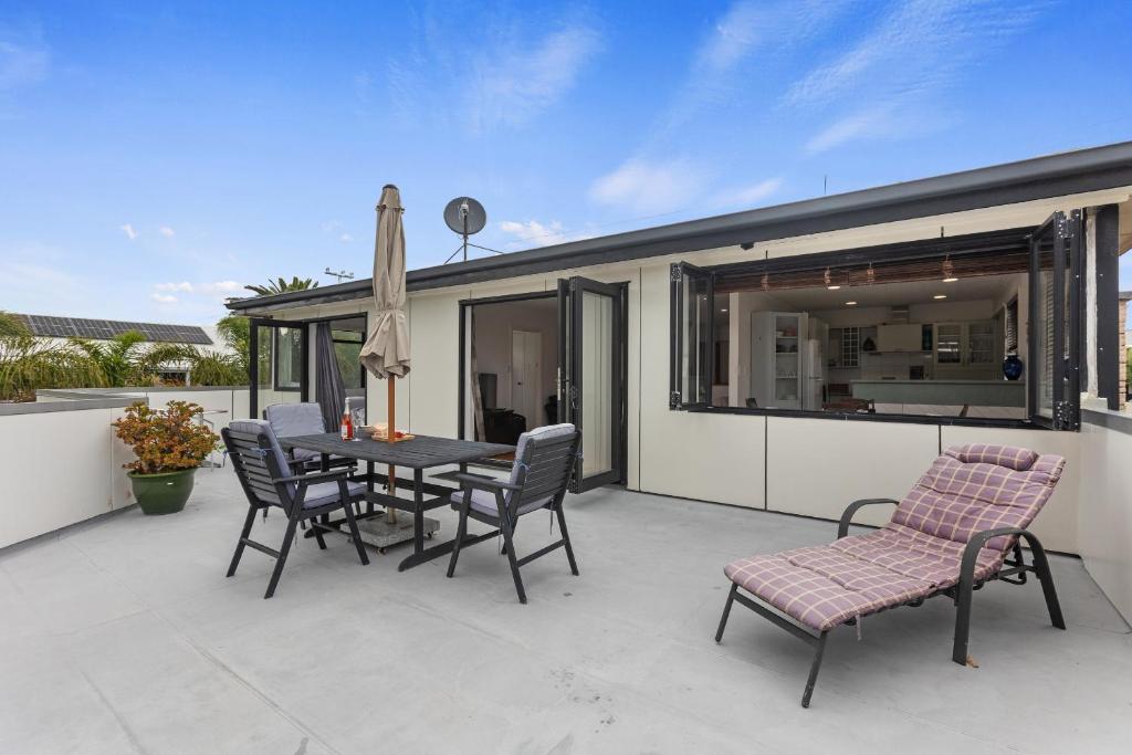 a patio with a table and chairs on a balcony at Beach Haven - Papamoa Beach Escape in Papamoa
