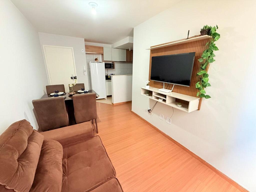 a living room with a couch and a flat screen tv at Apto Confortável - Supermercado Bahamas ao lado in Uberaba