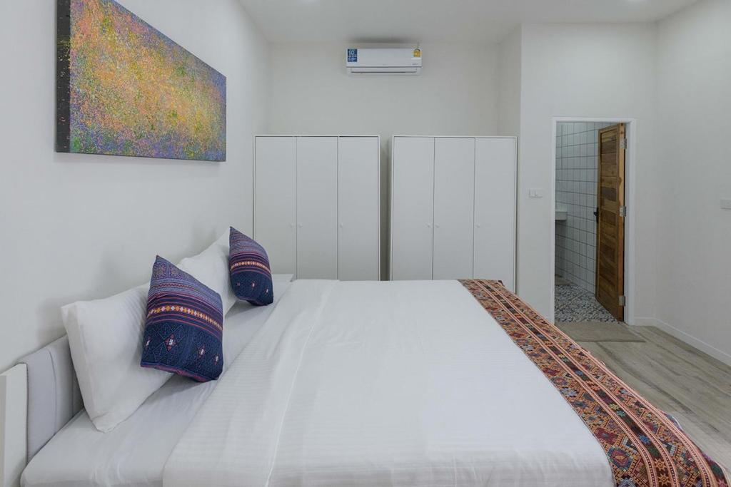 a bedroom with a white bed with two pillows at Coconut Breeze Villa #2 in Haad Chao Phao