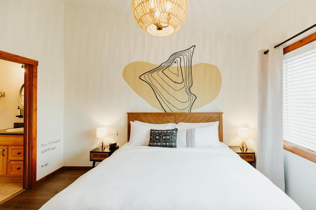 een slaapkamer met een wit bed en een tekening aan de muur bij Mt Cleveland at Switchback Suites in Kalispell