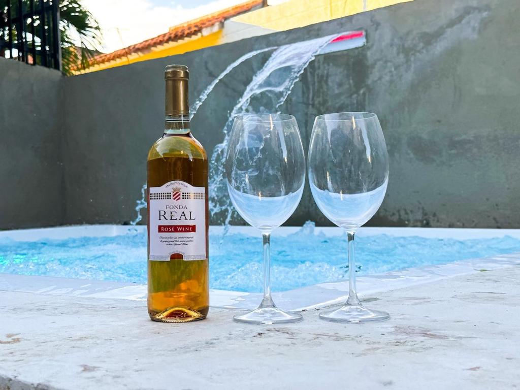 a bottle of wine and two wine glasses on a table at Haven Villa Retreat Jacuzzi Oasis in Mata los Indios