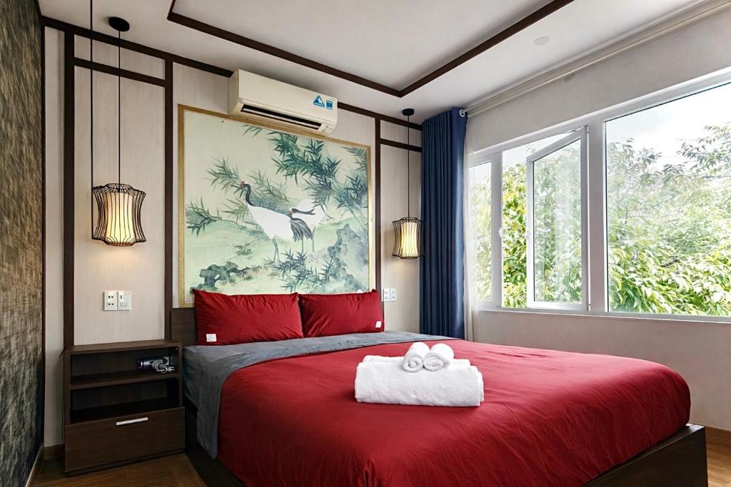 a bedroom with a red bed with two towels on it at Lagoon Homestay Hoi An in Hoi An