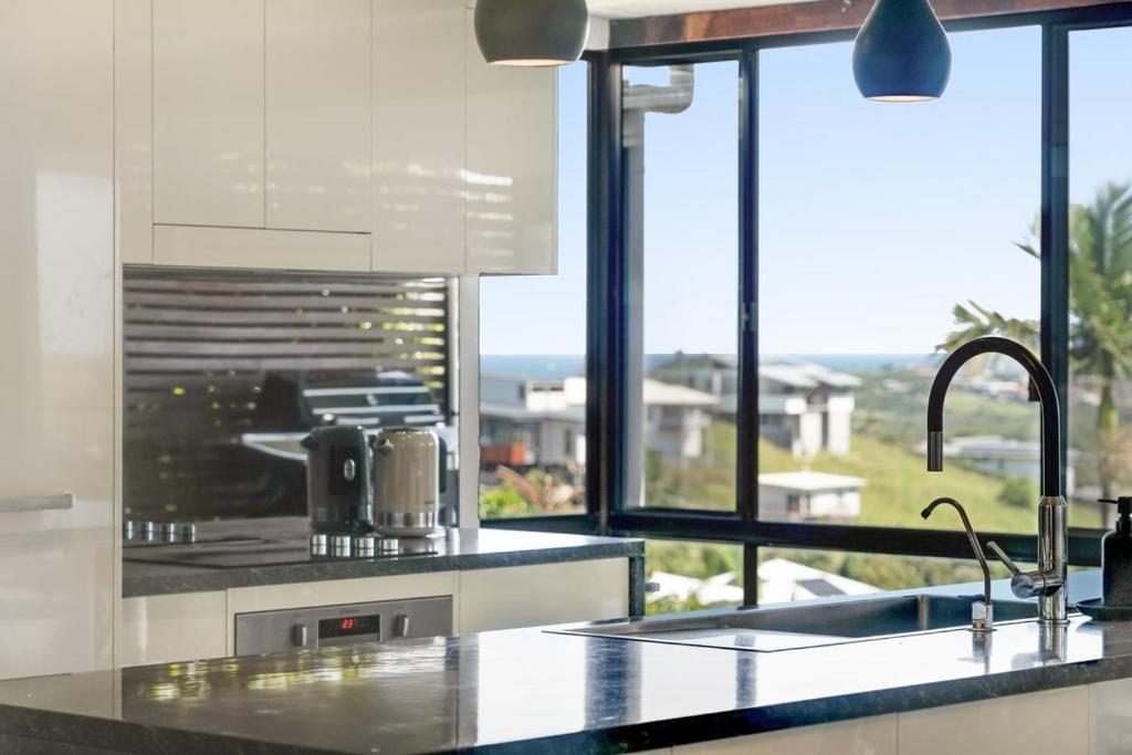 a kitchen with a counter with a sink and a window at The Break in Lennox Head