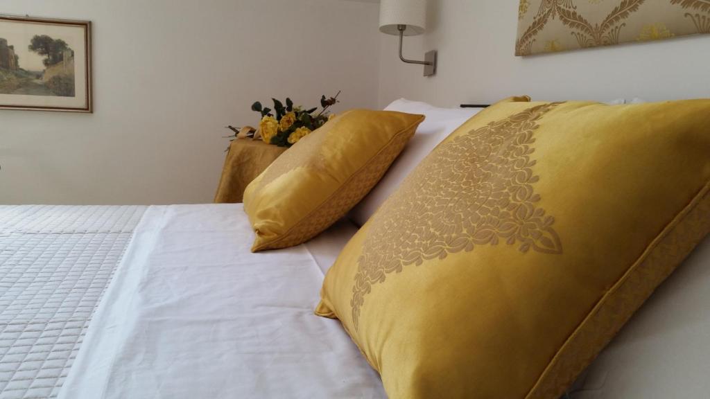 Una cama con manta amarilla y almohadas. en L'Insolita Reggia, en Caserta