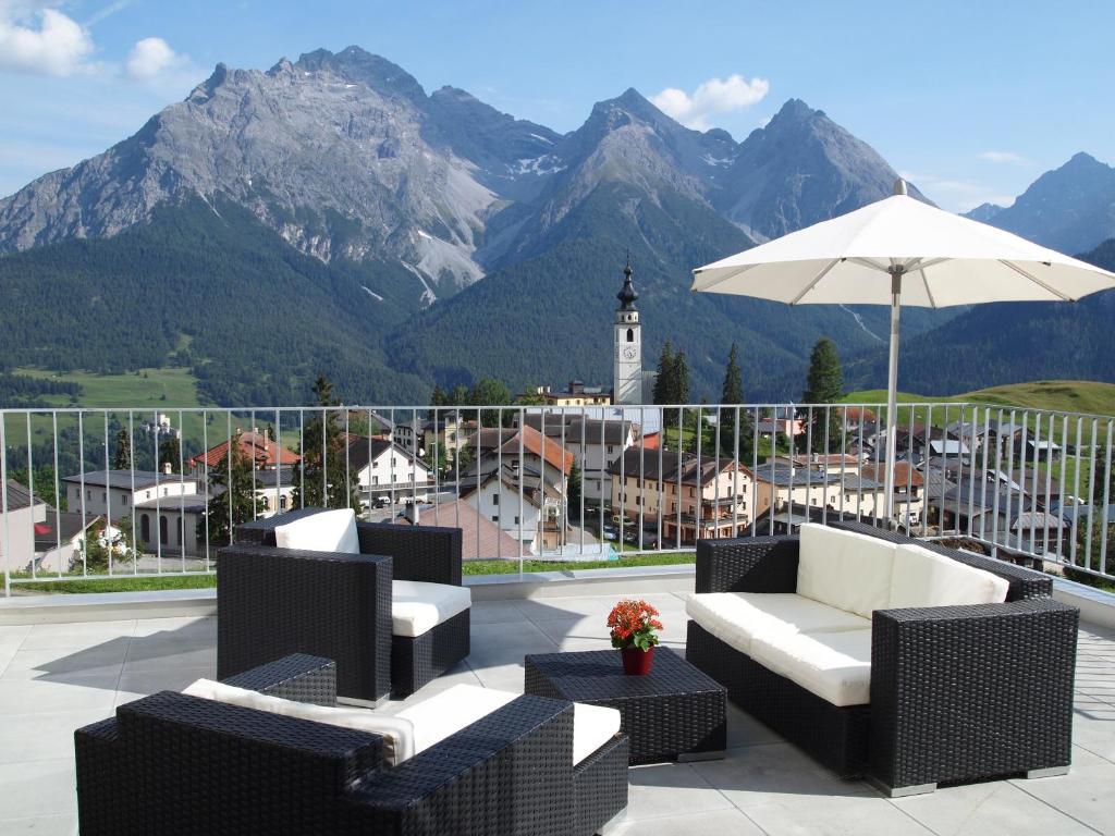 a patio with chairs and an umbrella and mountains at Fionas 256 in Ftan