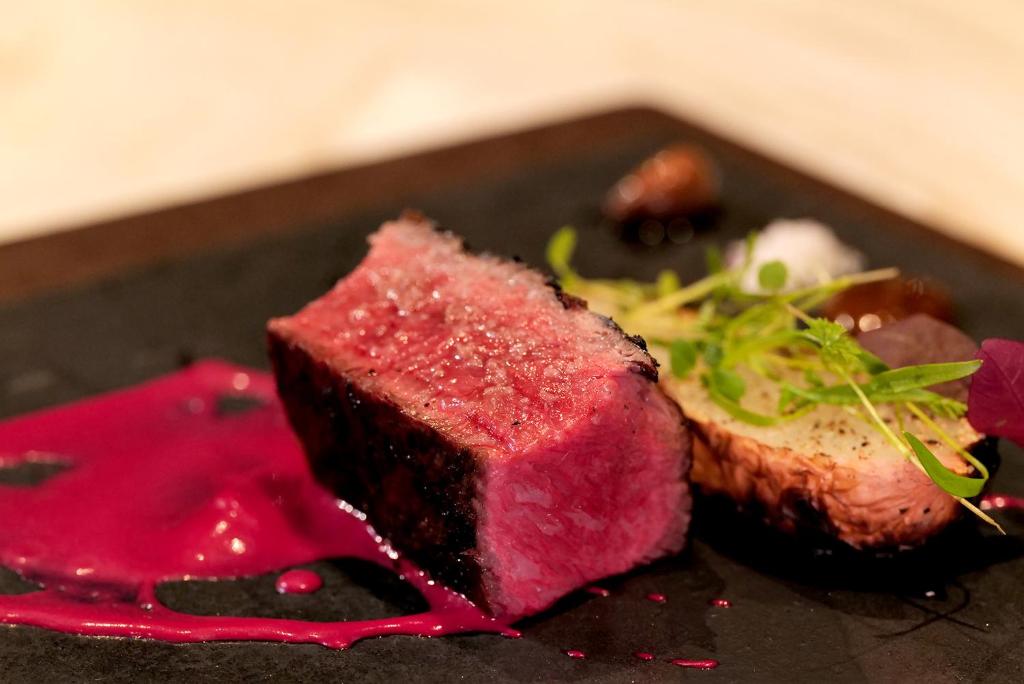 un piatto di cibo con un pezzo di carne e salsa rossa di THE BLESS Awaji a Sumoto